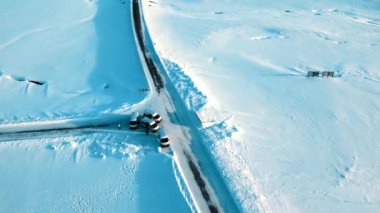 Soğuk İzlanda kışında donmuş ve karlı yoldaki kamyonetlerin hava görüntüsü.