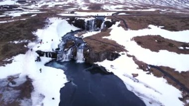 Kışın İzlanda 'daki ünlü Kirkjufell dağına kar yağan şelalenin insansız hava aracı görüntüsü