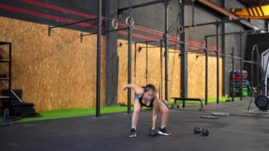 Spor salonundaki çamaşır makinesiyle ağırlık çeken Çinli bir kadının tam boy yan görüntüsü.