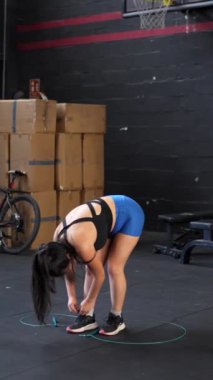 Asya 'lı bir sporcunun, çapraz antrenman salonunda ip atlarken tam boy ve önden çekilmiş portresi.