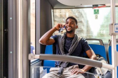 Afrikalı sıradan bir işadamı işe giderken otobüste oturuyor ve cep telefonuyla konuşuyor.