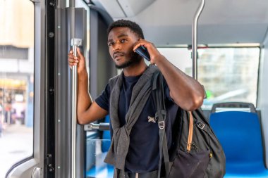 Meşgul Afrikalı sıradan iş adamı işe giderken otobüste cep telefonuyla konuşuyor.