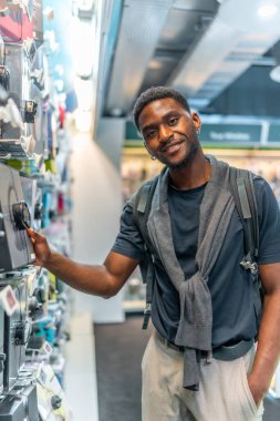 Elektronik mağazasındaki yakışıklı Afrikalı bir gencin dikey portresi.