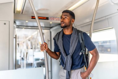 Neşeli ve kendinden emin Afrikalı genç adam şehir boyunca metroyla seyahat ediyor.