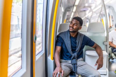 Sıradan ve genç Afrikalı iş adamı metroda oturmuş pencereden bakıyor.