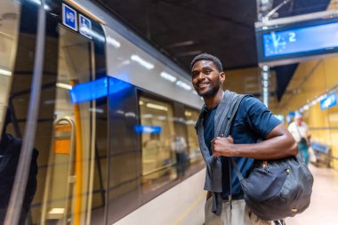 Afrikalı girişimci geceleyin şehirde platformda metroyu bekliyor.