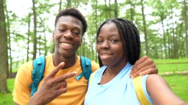 Afrikalı genç arkadaşlar dağda selfie çekerken parmaklarıyla zafer işareti yapıyorlar.