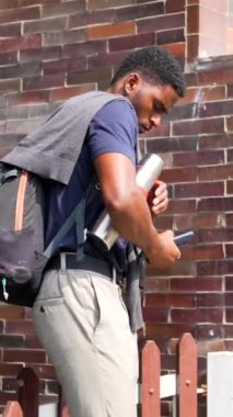 Genç Afrikalı iş adamı elinde bir dizüstü bilgisayar ve kahve termosuyla işe gitmek için bir yerleşim bölgesindeki evden ayrılıyor.