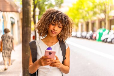 Latin güzeli genç bir kadın sokakta telefon kullanırken aşağıya bakıyor.