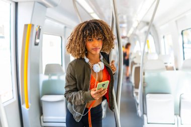 Telefonla metroda dikilen Latin bir kadının portresi.