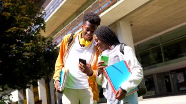 İki erkek ve kadın Afrikalı üniversite öğrencisi üniversite kampüsünün dışında telefon kullanıyor.