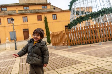 A smiling child in the parish church of San Miguel in Villalon de Campos decorated with a Christmas tree. Valladolid clipart