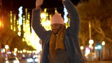 Afrikalı adam özgür ve kutsanmış hissediyor. Kollarını kaldırıyor ve şehirde bir Noel gecesinde yukarı bakıyor.