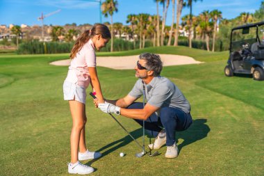 Koç, yazın lüks bir kursta altın derslerinde bir kızın duruşunu düzeltiyor.