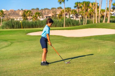 Lüks bir pistte tek başına golf oynayan beyaz bir gencin tam kenar görüntüsü.