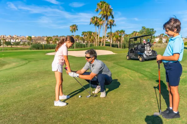 stock image Coach teaching a girl and her brother to play golf in summer in a luxury course