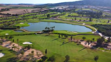 Yeşil çimenleri ve gölü olan lüks bir golf sahasının geniş hava manzarası.