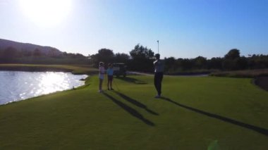 Koç bir kıza ve kardeşine lüks bir kursta golf oynamayı öğretiyor.