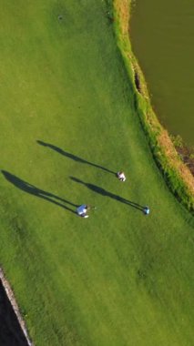 Yeşil lüks altın bir pistte üç kişinin havadan görünüşü