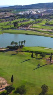 Yeşil çimenleri ve gölü olan lüks bir golf sahasının geniş hava manzarası.