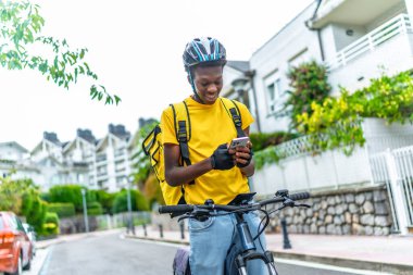 Bisikletli Afrikalı kurye cep telefonu kullanarak GPS ile konumunu kontrol ediyor.