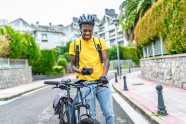 Genç bir Afrikalı teslimatçı konumu kontrol etmek için telefon kullanıyor.
