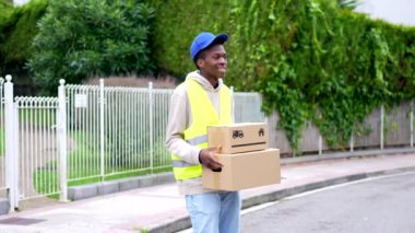 Afrikalı genç teslimatçı şehirde teslim edilecek paketleri taşıyor.