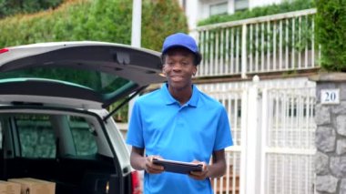 Paketleri teslim etmek için minibüsle çalışırken tablet kullanan neşeli bir Afrikalı adam.