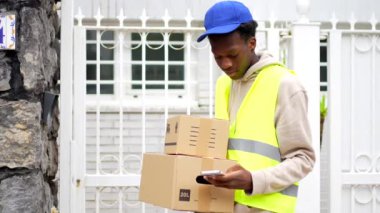 Afrikalı teslimatçı bir evin girişine elinde bazı paketler ile geliyor.