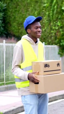 Afrikalı genç teslimatçı şehirde teslim edilecek paketleri taşıyor.
