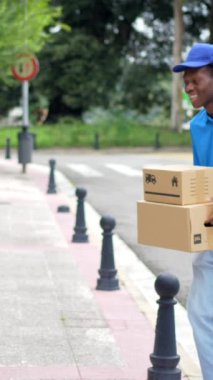 Afrikalı bir adam, yetişkin bir adama paket teslim ediyor. Bir yerleşim yerindeki evin girişinde bekliyor.