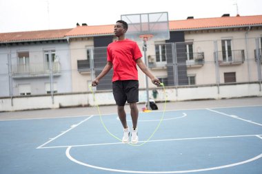 Şehir basketbol sahasında ısınan genç bir Afrikalı adamın dinamik çekimi.