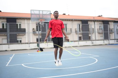 Genç adam şehirde basketbol sahasında çalışırken okulu asıyor.