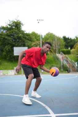 Açık hava tesislerinde antrenman yapan Afrikalı Amerikalı bir basketbolcunun dikey fotoğrafı.