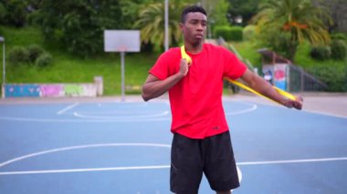Afrikalı gençler açık hava basketbol sahasında elastik bant kullanarak ısınıyorlar.