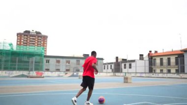 Açık hava mavi basketbol sahasında top atan bir basketbolcunun videosu.