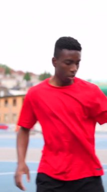 Bir top atmak için zıplayan Afrikalı bir erkek basketbolcunun dikey videosu.