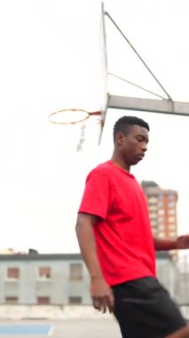 Afro-Amerikan bir basketbolcunun açık havada tek başına salya akıtırken tam boy dikey videosu.