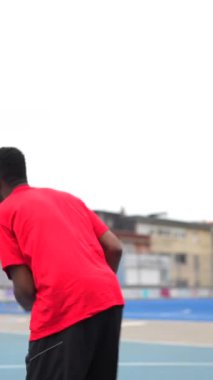 Açık hava tesislerinde antrenman yapan Afrikalı Amerikalı bir basketbolcunun dikey videosu.