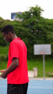 Açık hava basketbol sahasında ip atlayan Afrikalı bir gencin dikey videosu.