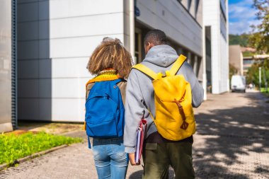 Üniversite kampüsü boyunca yürüyen iki çoklu etnik öğrencinin arka görünüşü