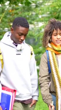 Düşük açılı iki farklı öğrencinin konuşuyor ve üniversitenin dışında cep telefonunu paylaşıyorlar.