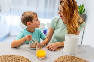 Okul çocuğu ve annesi, okula gitmeden önce kahvaltıda bisküvi yiyorlar.