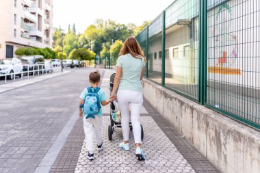 Okulun ilk gününde bir anne ve oğulun el ele tutuşup okula gidişinin arkası.