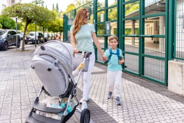 Anne, okuldaki ilk günümden sonra bebek arabasını itiyor ve çocuk eve dönüyor.