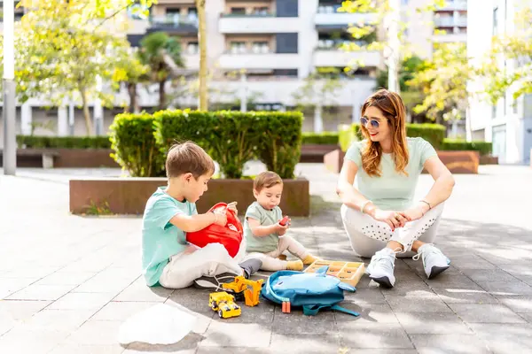 Beyaz bir anne ve çocuğun şehir parkında oyuncaklarla oynarken çekilmiş uzun bir fotoğrafı.