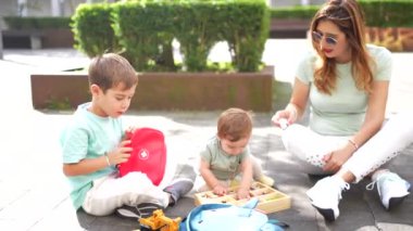 Beyaz bir anne ve çocuğun şehir parkında oyuncaklarla oynarken çekilmiş uzun bir fotoğrafı.