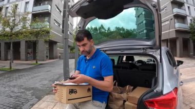 Mavili teslimatçı. Paketleri ve adresi kontrol ediyor.