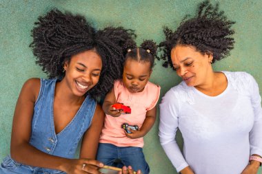 Cep telefonunu kullanıp parkta oynayan çok nesilli bir Afrikalı kadın. Aile kavramı