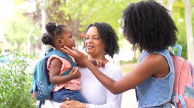 Üç kuşak Afrikalı kadın aile halka açık bir parkta bir kızı ve oyuncakları taşıyor.